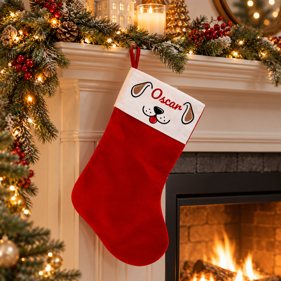 A red Christmas stocking with a white cuff hangs from a fireplace mantel decorated with green garlands, warm string lights, pinecones, and red berries. The cuff is personalized with the name 'Oscar' in red script and a black-and-red dog face illustration.