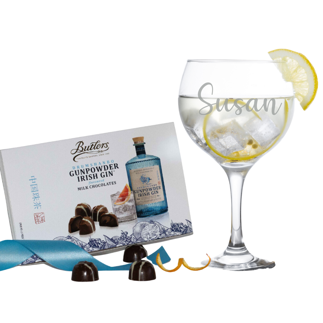 A gift set for gin lovers, featuring a personalized gin glass with the name 'Susan' etched on it, accompanied by a box of Butler's Gunpowder Gin chocolates and presented with a slice of lemon and a blue ribbon.