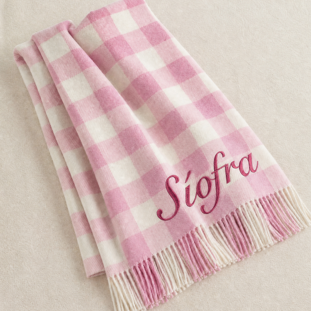 A folded pink and white gingham check blanket with fringe and the name 'Siofra' embroidered in pink script, displayed on a light beige textured background.