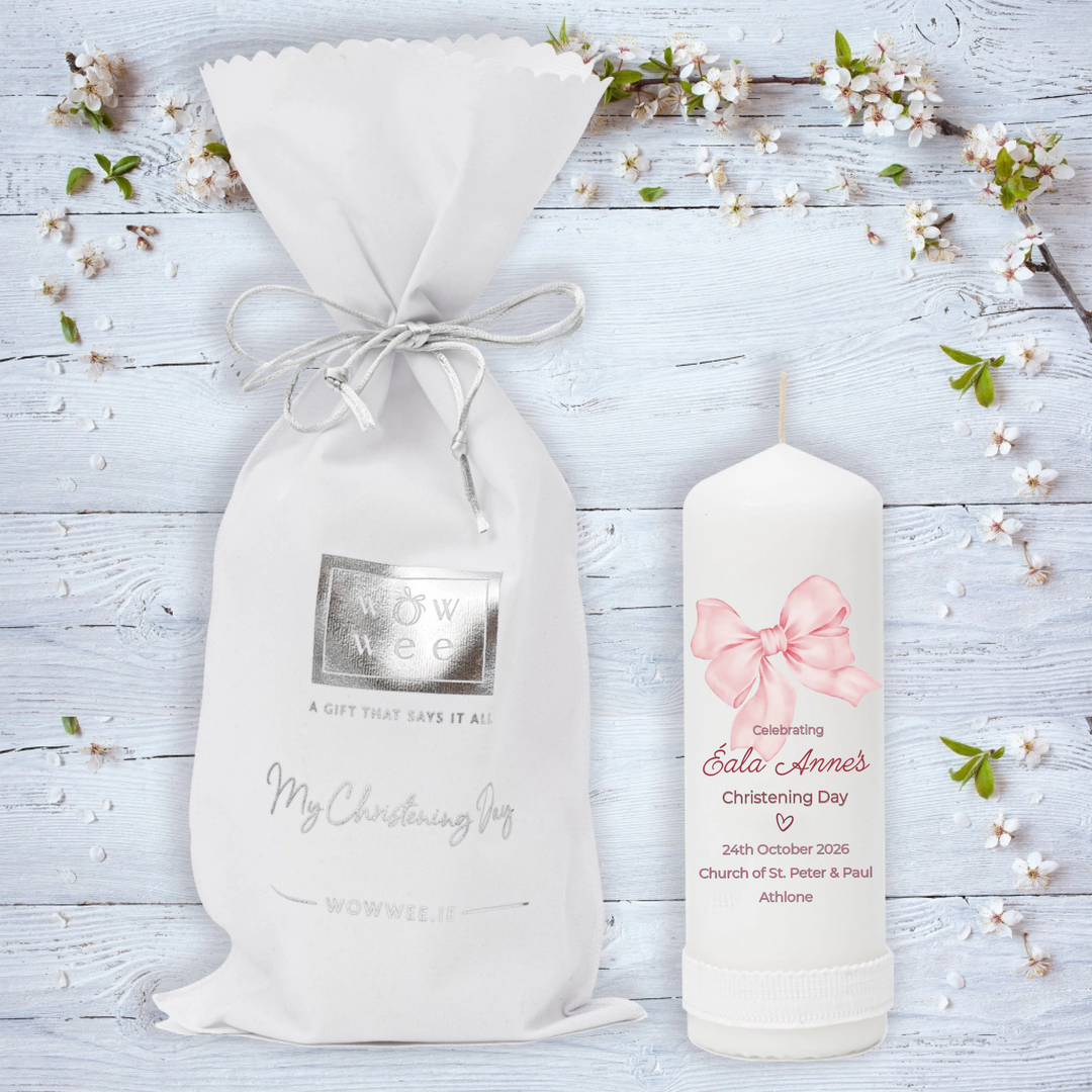 White gift bag and candle with floral decorations on a light wooden background