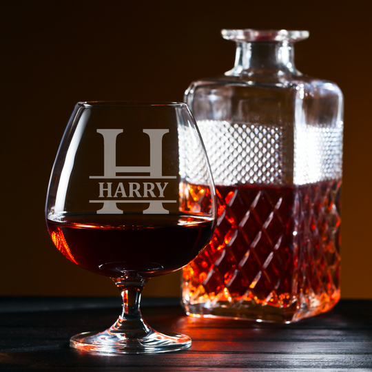 Whiskey glass and decanter with 'HARRY' engraving on a wooden surface.