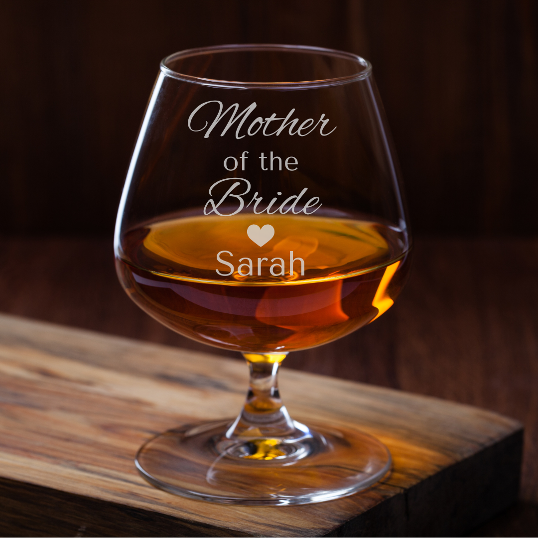 Brandy glass with 'Mother of the Bride Sarah' engraving on a wooden surface.