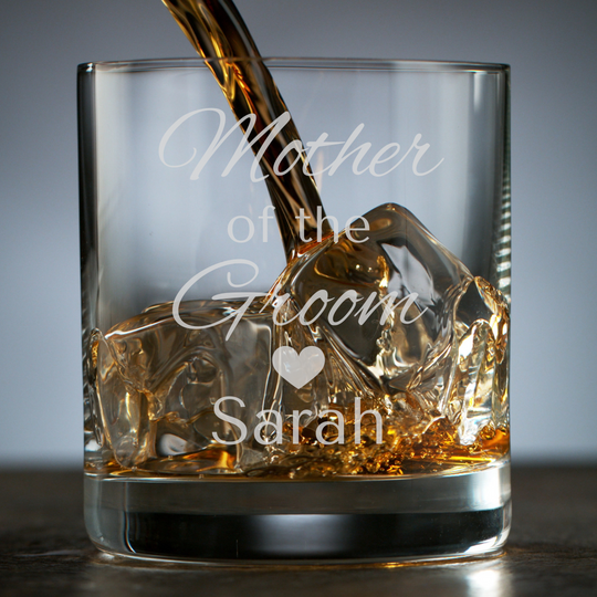 Glass with engraved text 'Mother of the Groom Sarah' being filled with whiskey.