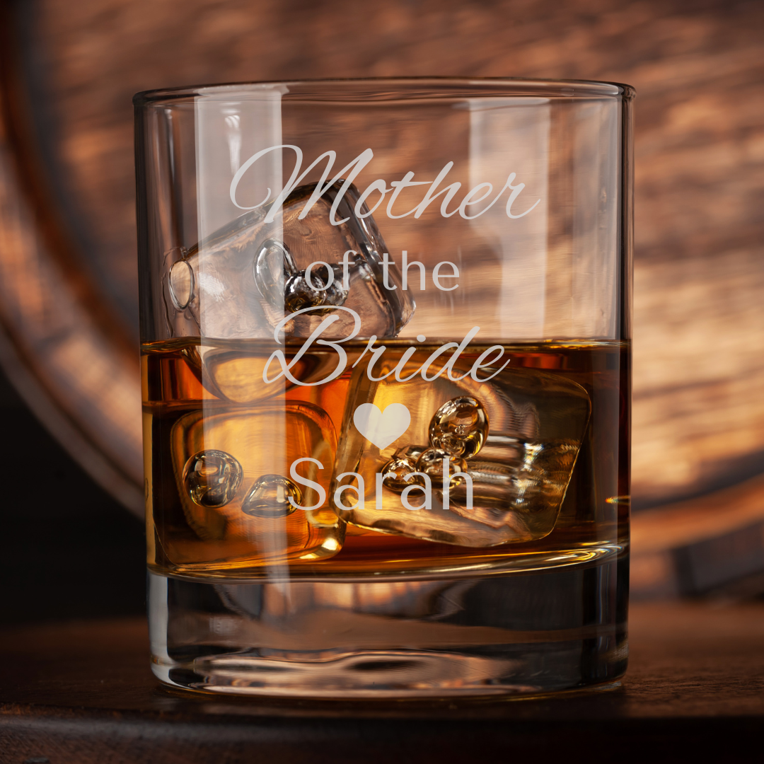 Glass of whiskey with ice and 'Mother of the Bride Sarah' engraving on a wooden background