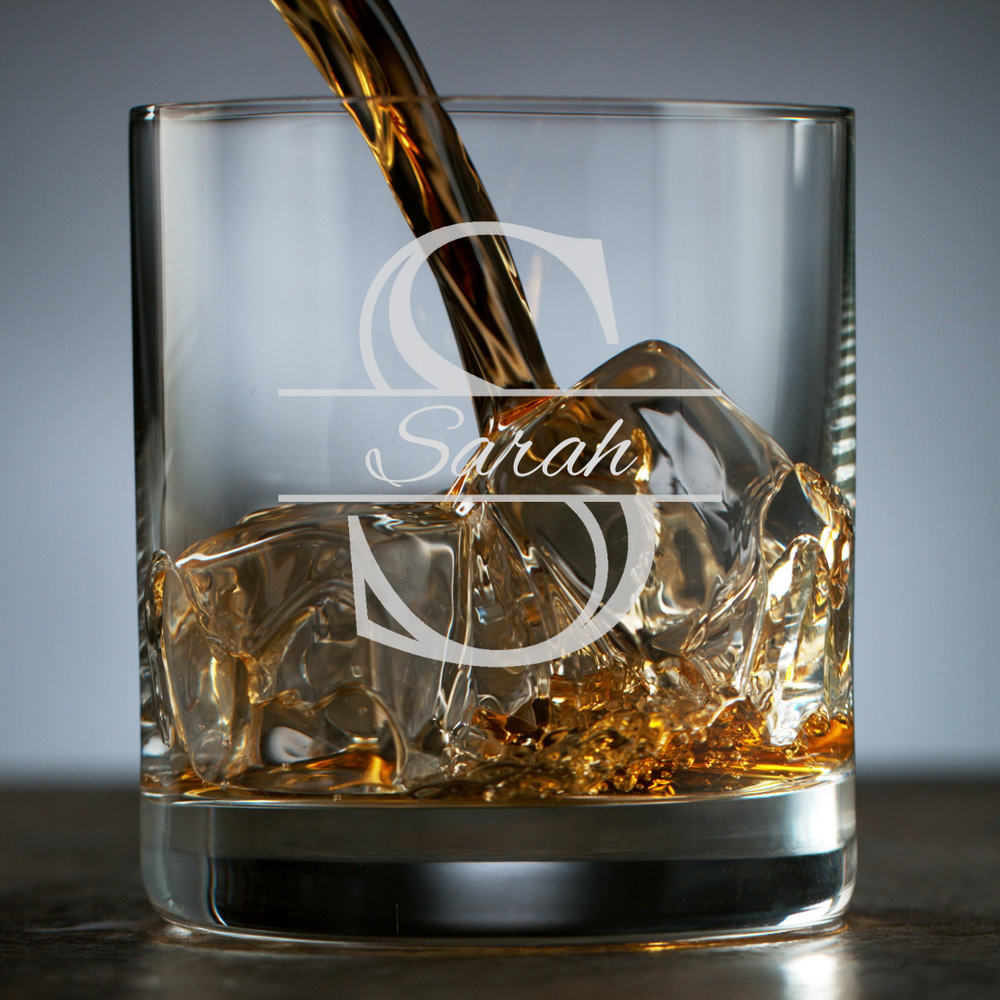 Whiskey being poured into a glass with ice cubes, featuring a brand logo on the glass.