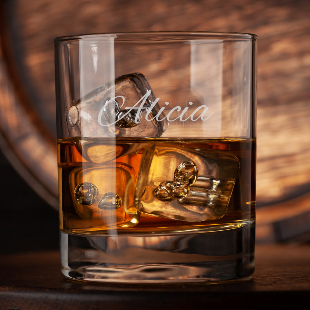 Glass of whiskey with ice cubes and 'Alicia' engraving on a wooden background