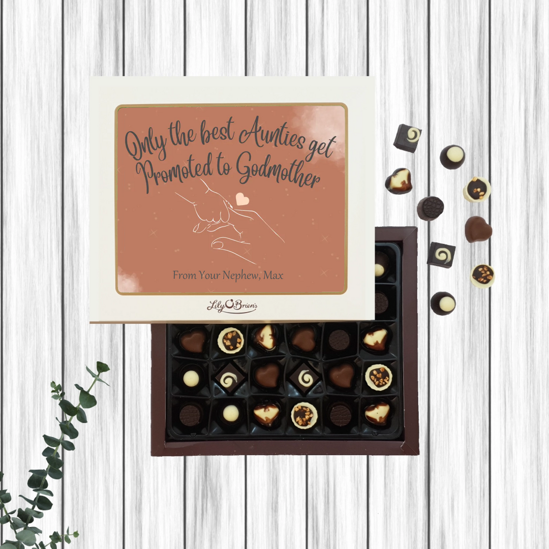 Box of chocolates with a personalised card for Godmother on a wooden surface