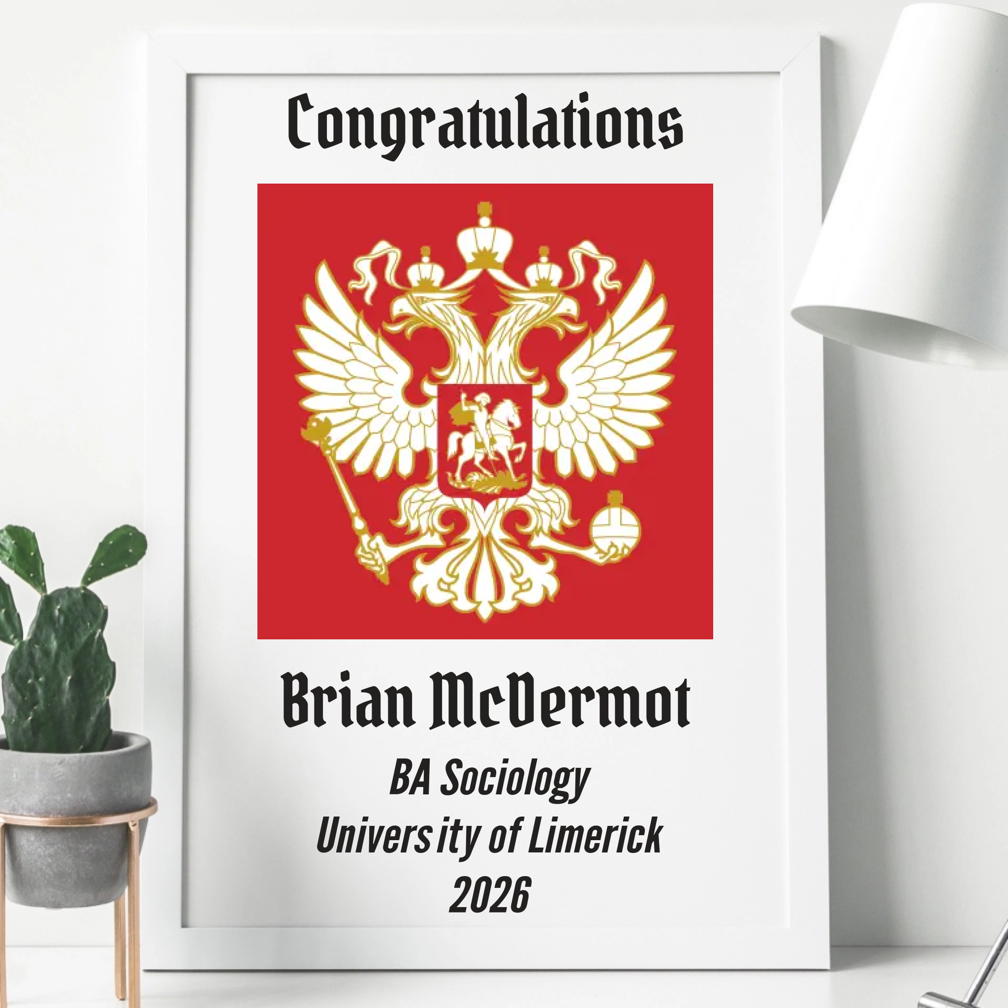White wooden frame with a personalised graduation print. the print is A4 in size and is personalised with the graduate name, last name, university, degree and year. Upload your own university crest