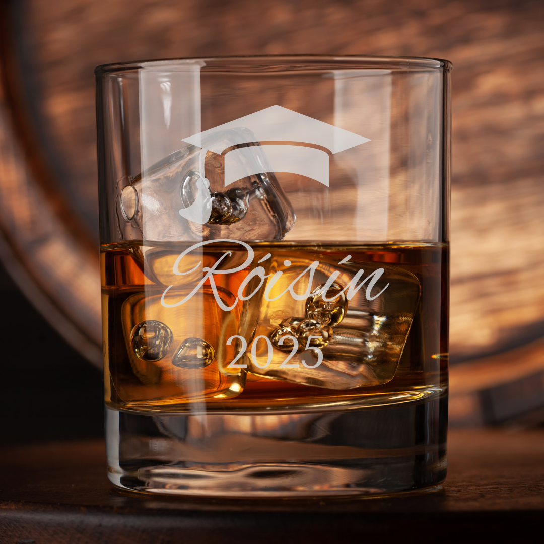 Glass of whiskey with ice cubes and engraved text on a wooden background