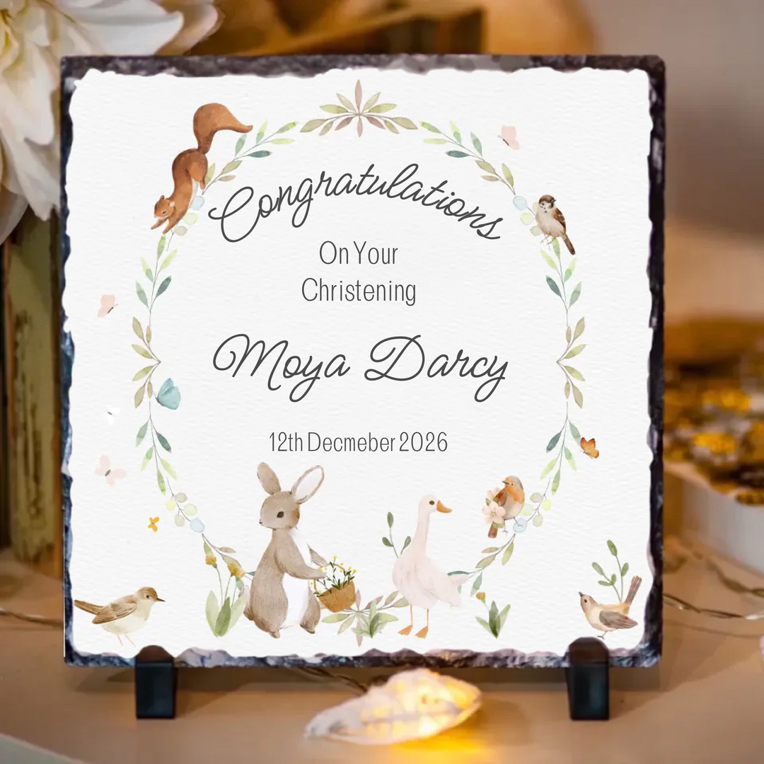 Personalized christening congratulations slate with decorative elements on a table.
