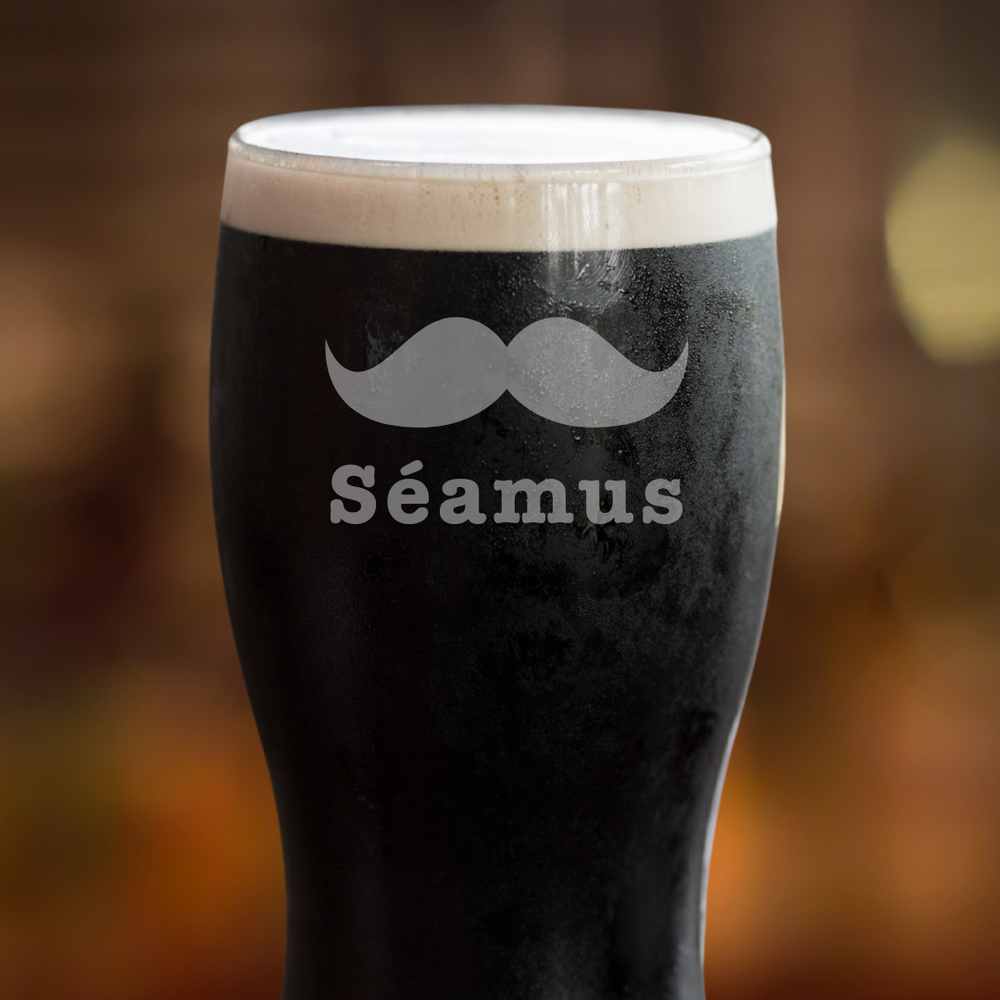Black beer glass with a mustache design and 'Séamus' text on a blurred background