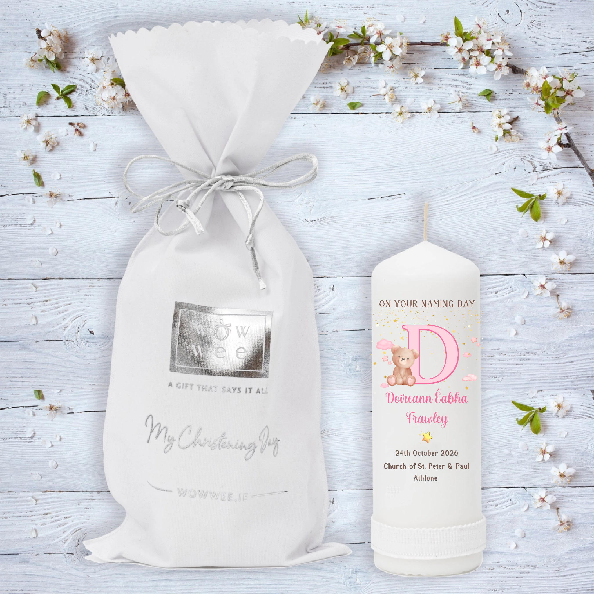 A personalized Naming Day gift set featuring a white drawstring pouch with a silver foil logo and a white candle. 