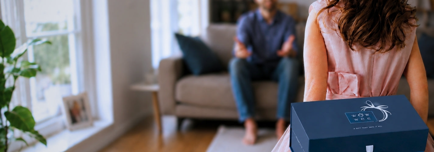 Little girl holding a WowWee gift box with a blurred background of a living room.